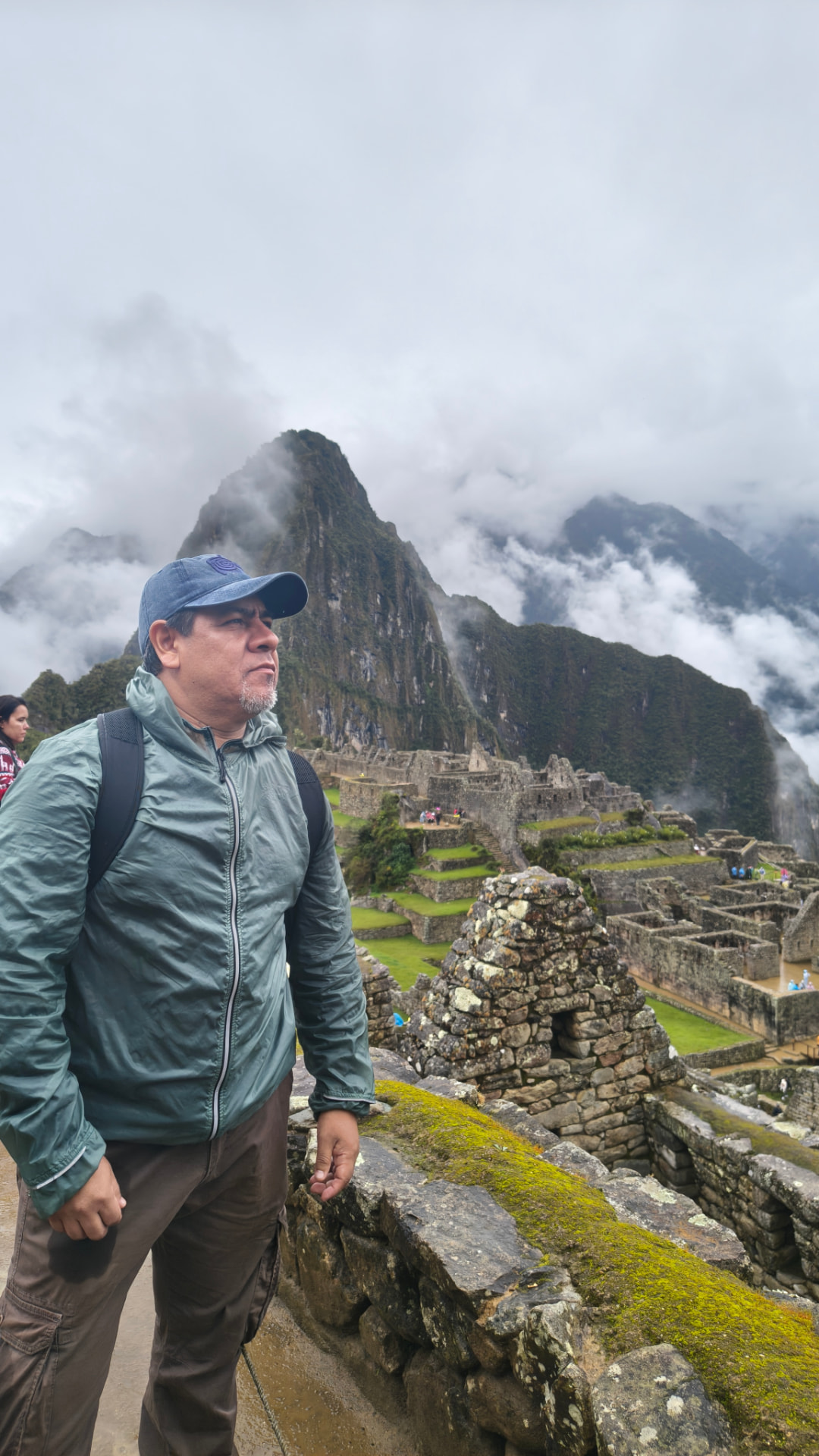 Luis, tour leader da UP Level, nas ruínas de Machu Picchu, com montanhas e nuvens ao fundo